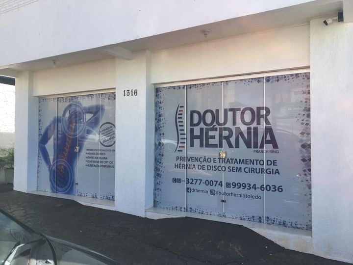 Fachada da unidade Doutor Hérnia em Toledo, com o nome da clínica nos vidros e o número 1316 na parede