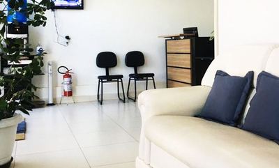 Sala de espera com sofá, almofadas e cadeiras